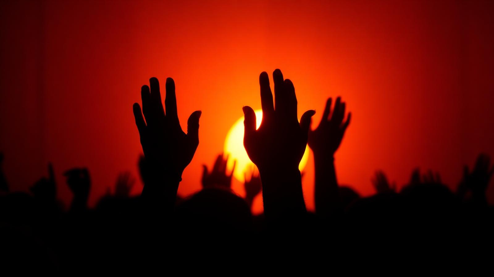 Hands raised against a fiery sunset